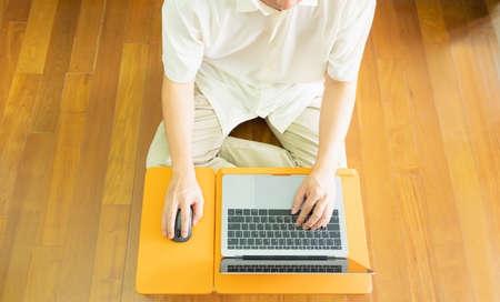 Top view of half body of anonymous professional business man or employee smart work at home by using mouse and typing notebook or laptop to remote working via online internet network on computerの写真素材