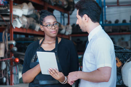 Woman work with man, she angry him. Diversity of two people, black African worker woman angry caucasian business manager in factory-warehouseの写真素材