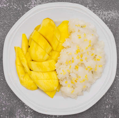 Thai sticky rice with mango on plate and stone background, sweet thai dessert cuisine made from sticky rice, mango, coconutの写真素材