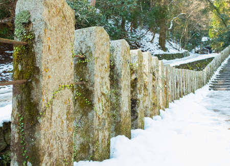 stone pillar on mountain forest path with snow path in winter, pathway with stone post in forest on mountain at asia japanの写真素材
