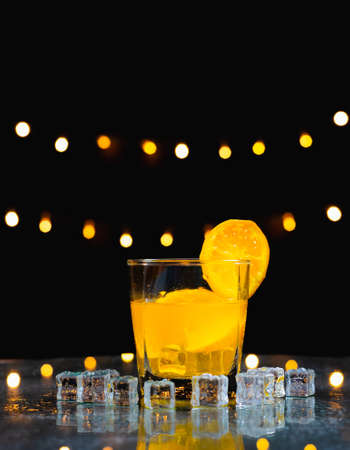 close up focus at orange juice with slice fresh orange on glass rim, behind ice on table with light background, bartender prepare fruit cocktail or fresh juice for drinking in party at barの写真素材