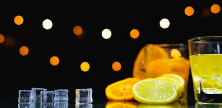 close up focus at slice fresh lemon, beside slice fresh orange, glass, ice on table, bartender prepare fruit cocktail or fresh juice for drinking in party at barの写真素材