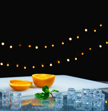 slice fresh orange on cutting board near leaf, ice on table, bartender prepare fruit cocktail or fresh juice for drinking in party at barの写真素材