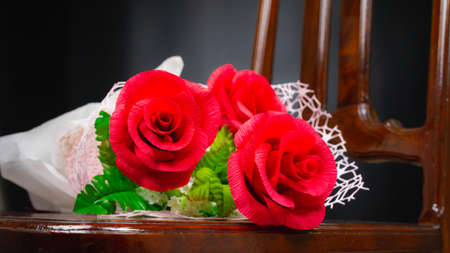 red rose flower in bunch on wood chair, beautiful elegance red roses flower of love inspiration in anniversaryの写真素材