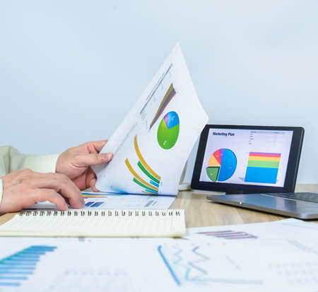 man working data graph document near notebook, tablet, laptop, professional businessman busy work on the business data graphの写真素材