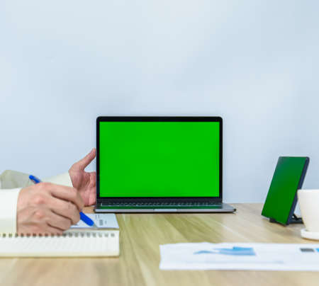 close up green screen on laptop with working environment of worker for making meeting presentation, professional businessman busy work on the business data graphの写真素材