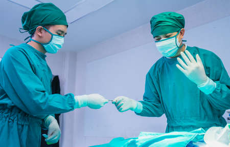 doctor receive scalpel from doctor assistant in operating room, operation or surgery room in hospital for doctor and patientの写真素材