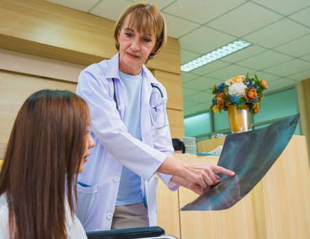 caucasian women doctor explain xray result to patient, doctor with stethoscope medical treat health of patient at hospitalの写真素材