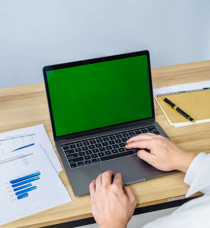 close up working with laptop and graph on working desk, green screen for making meeting presentation, professional businessman busy work on the business data graphの写真素材