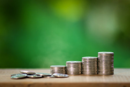 Stack of coins on wooden table with green bokeh background.の写真素材
