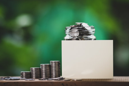 Coins stacked on each other in different positions with white card and blurred background.の写真素材