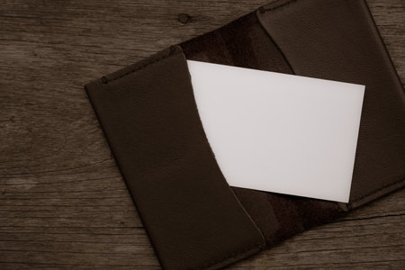 Blank business card on brown leather wallet on old wooden background.の写真素材