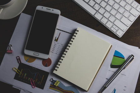 Business workplace with smart phone, supplies and coffee cup on wooden tableの写真素材