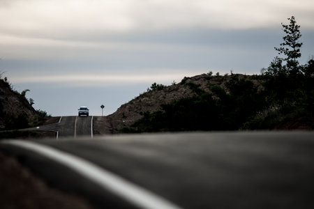 Car driving on the road in the mountains with a cloudy sky.の写真素材