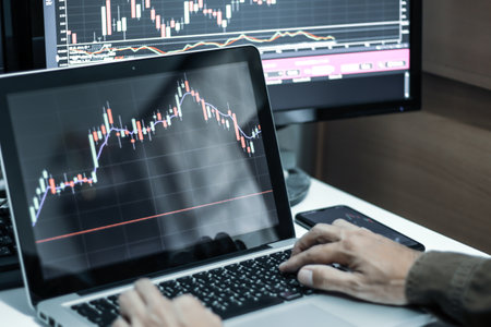 Stock market data on monitor. Businessman working with laptop computer.の写真素材