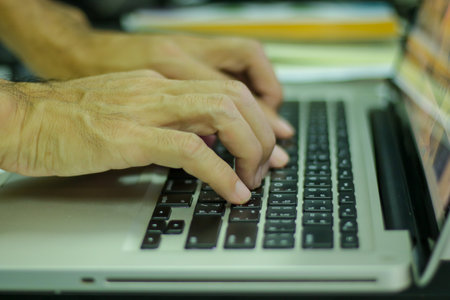 Close-up of a man's hands typing on a laptop keyboardの写真素材