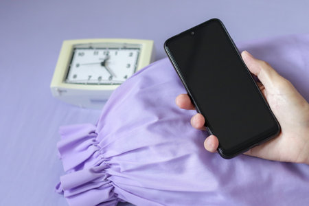 A black smartphone in man hand on purple bedの写真素材