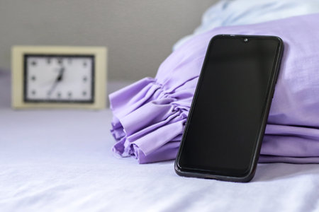 A black smartphone on purple bedの写真素材