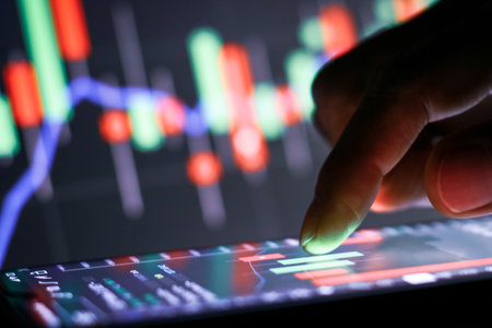 Businessman finger touching screen on smartphone with stock market graph at night.