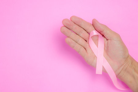 breast cancer awareness ribbon on hand palm and on pink backgroundの写真素材