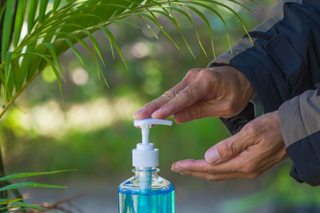 Asian people hands pressing alcohol antiseptic gel,prevent infection,outbreak of Covid-19 or virus with green naturalの写真素材