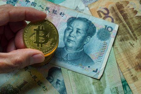 Golden bitcoin on Chinese yuan banknotes background, business conceptの写真素材