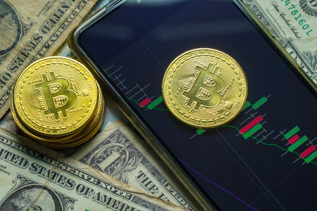 Golden Bitcoin and dollar banknotes on smart phone with graph chart.の写真素材