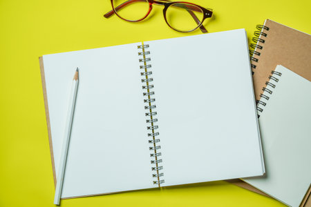 Top view Notebook with blank page on yellow background
