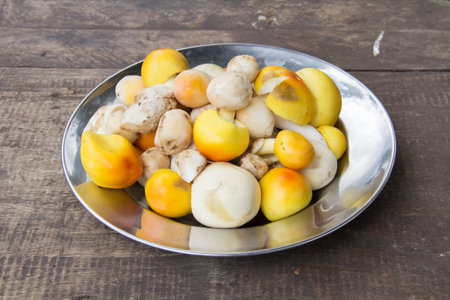 Fresh yellow mushroom in the stainless bow on wooden table.の写真素材