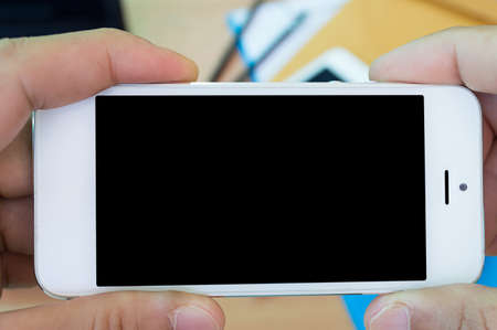 Hand holding the smartphone on desk background