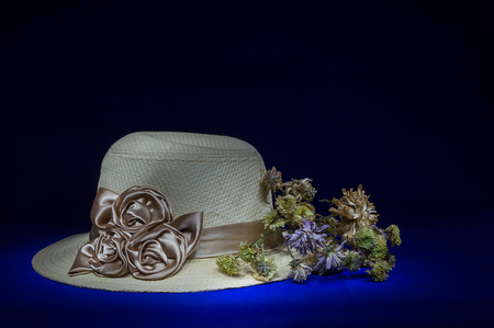 Straw hat with flowers on black background-still lifeの写真素材