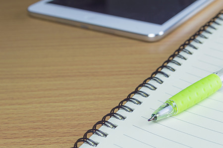 Pen with notepad and tablet on the wooden desk backgroundの写真素材