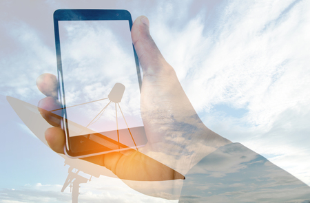 Double exposure Satellite dish and Hand with smart phone social media conceptの写真素材