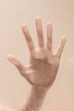 close up of the hand of young girl putting her hand against a depolished glass from behind