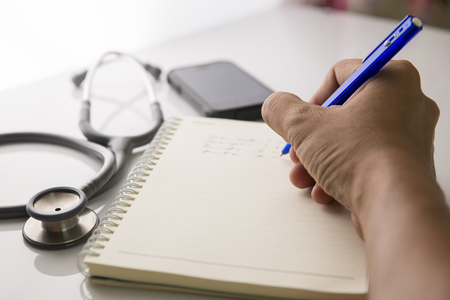 Writing on the medical form with the stethoscope nearbyの写真素材