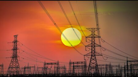 The sun silhouettes numerous hydro tower as it sets.の写真素材