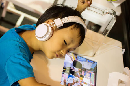 Asian kid play computer internet games and wear headset to communicate