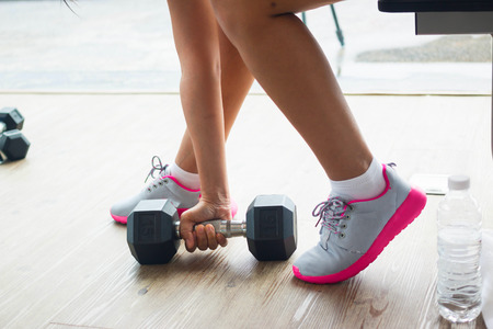 Muscular woman doing push-ups on dumbbells in gymの写真素材