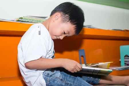 Cute little boy reading book in the libraryの写真素材