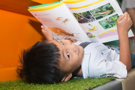 Cute little boy reading book in the library
