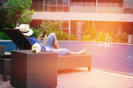 man in hat sunbathing on chair by the poolの写真素材