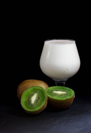 Ripe whole kiwi fruit and half kiwi with milk isolate on Black backgroundの写真素材
