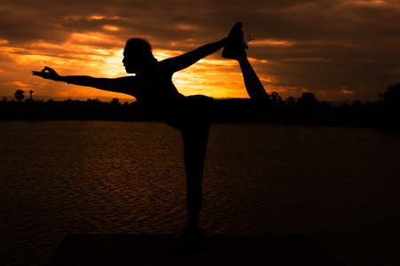 Women are playing yoga at Reservoir area with Sunsetの写真素材