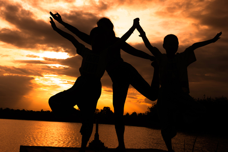 Women and boy are playing yoga at Reservoir area with Sunsetの写真素材