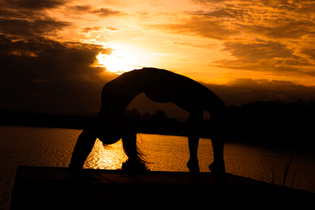 Women are playing yoga at Reservoir area with Sunsetの写真素材