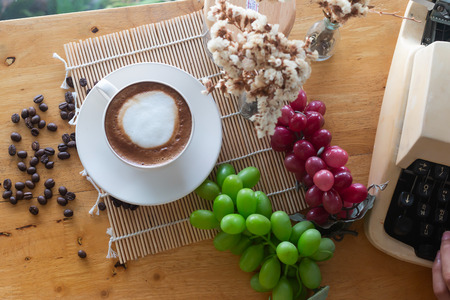 hot coffee in cup and coffee bean and typewriter and Grape fruit on the wooden tableの写真素材