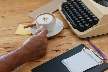 hot coffee in cup and coffee bean and typewriter on the wooden tableの写真素材