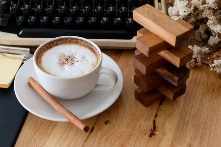 hot coffee in cup and coffee bean and typewriter on the wooden tableの写真素材