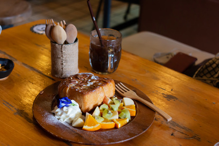 Honey toast Topped with condensed milk with Mixed Fruit on wood table