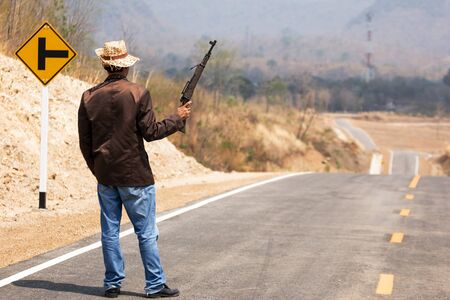 cowboy with a gun on beautiful road in the countryside Of Thailand Through beautiful mountainsの写真素材